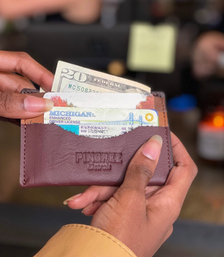 
                  
                    Load image into Gallery viewer, Whittier Wallet filled with cash and cards at checkout counter. Made in Detroit Michigan from upcycled automotive leather.
                  
                